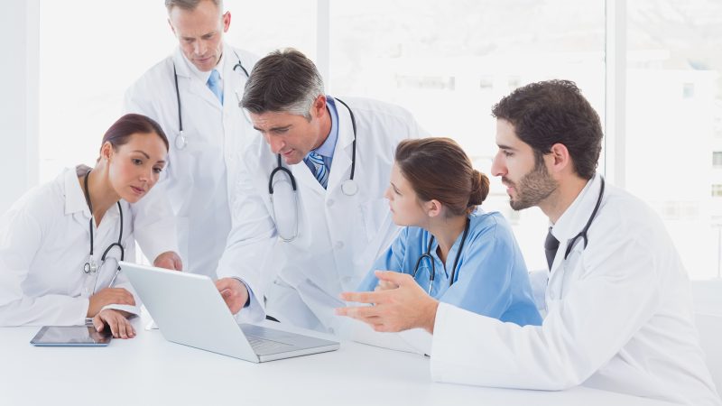Doctors using a laptop together at work